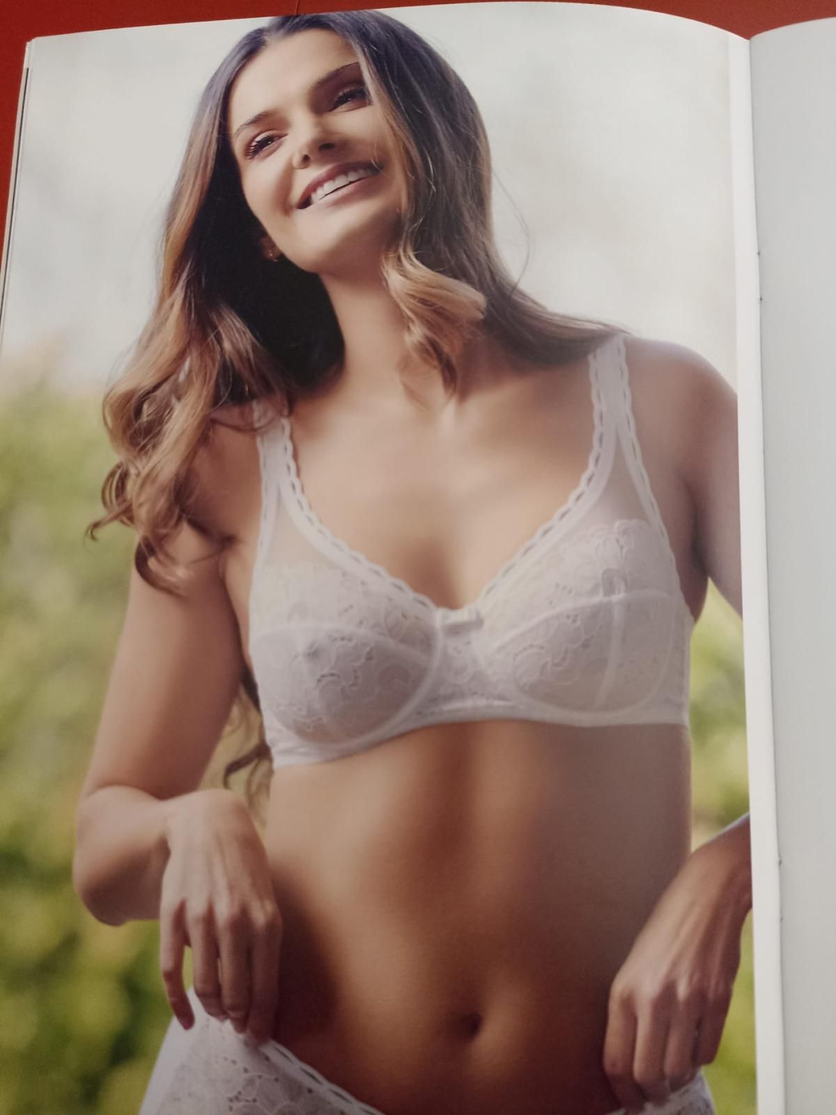 Donna sorridente all'aperto, in reggiseno e biancheria intima di pizzo bianco.