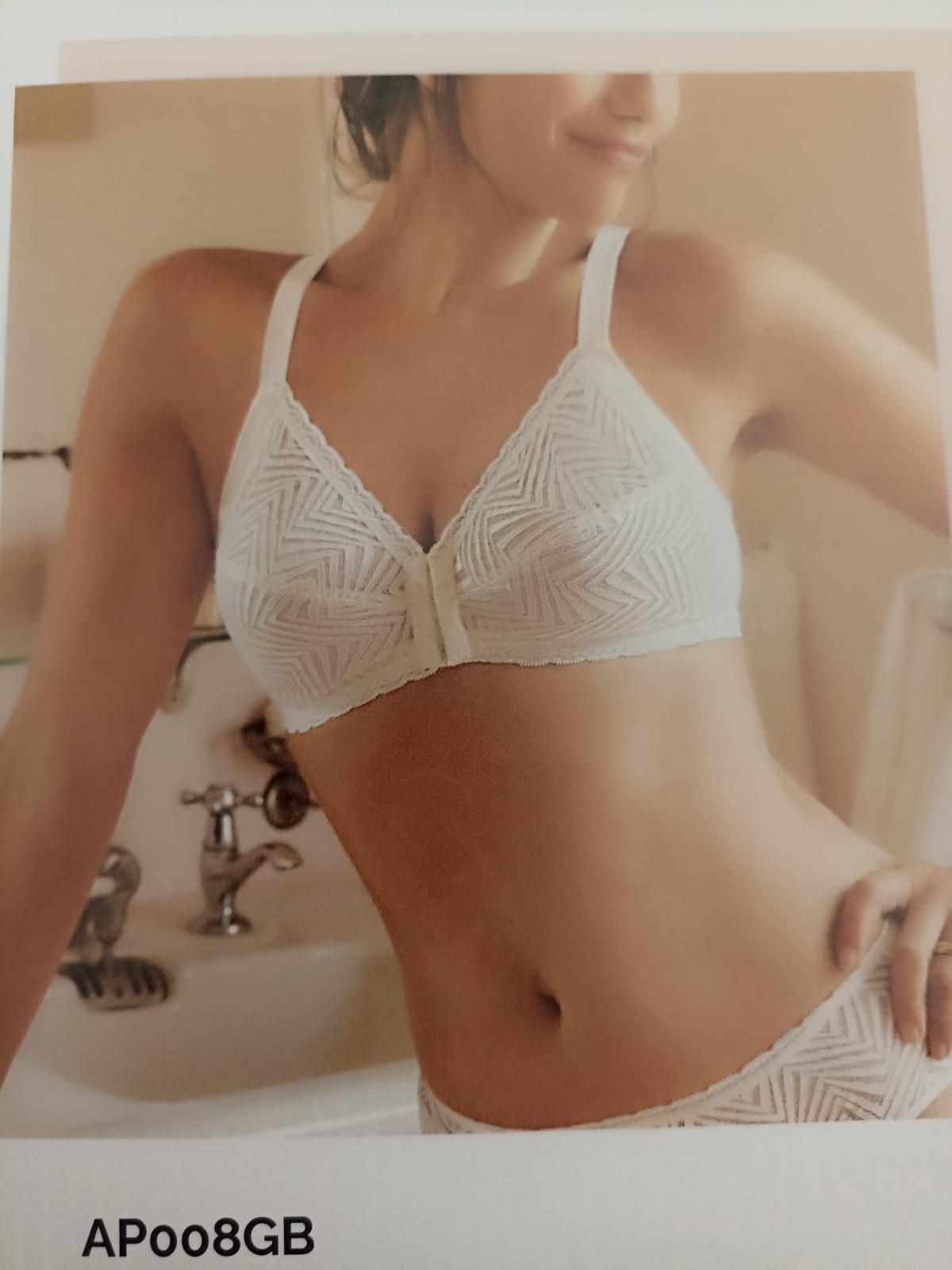 Donna in reggiseno e biancheria intima bianchi in posa in un bagno.