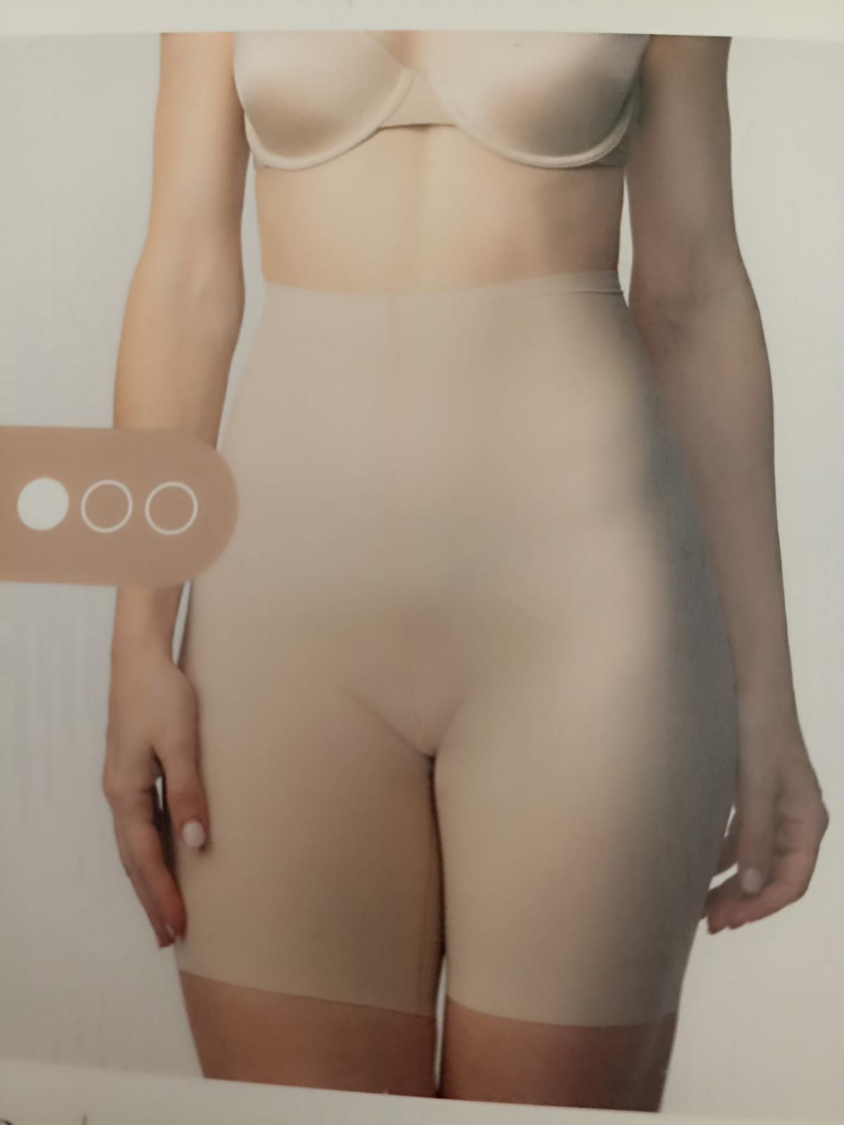 Donna che indossa pantaloncini modellanti beige e reggiseno.