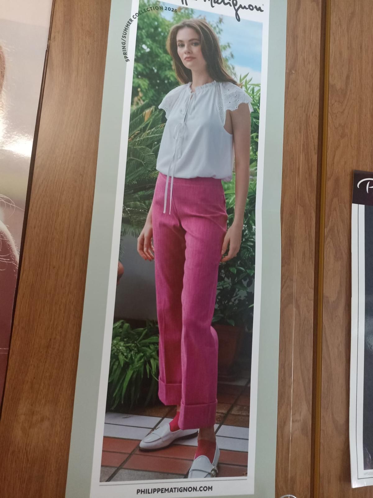 Donna in piedi su un patio, con indosso un top bianco, pantaloni rosa e scarpe bianche.