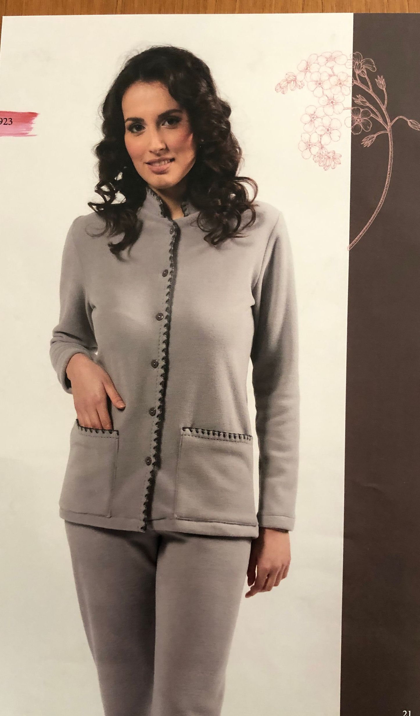 Donna sorridente con cardigan e pantaloni grigi. Tasche e bordi rifiniti con dettagli.