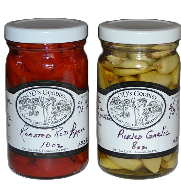 Two jars of OD's Goodies: roasted red peppers and pickled garlic. Jars have white lids and labels with a logo.