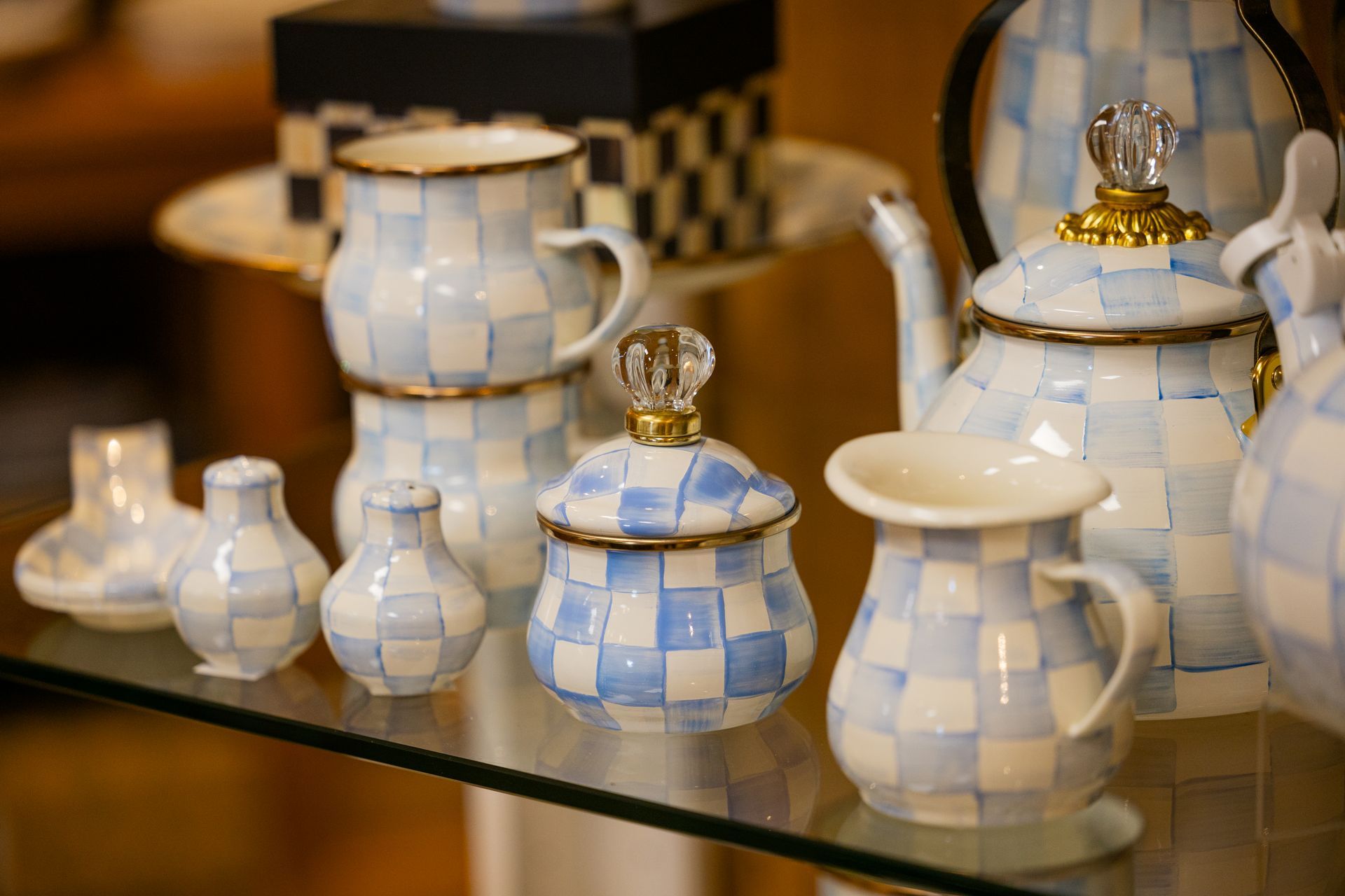 Blue-and-white ceramic teapot set with gold accents displayed on a shelf