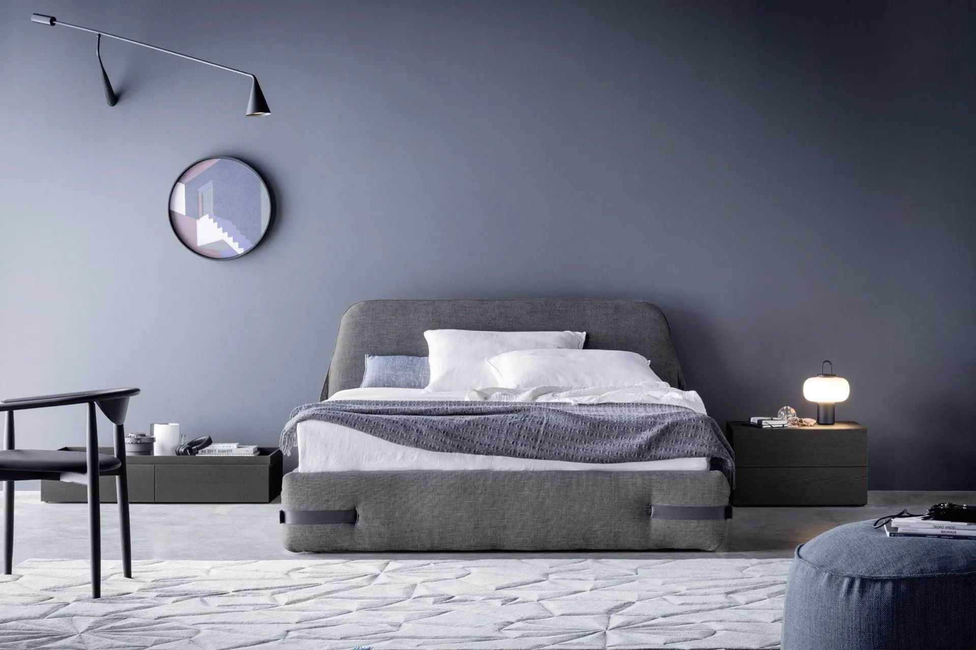 Camera da letto minimalista sui toni del grigio con letto basso, specchio rotondo