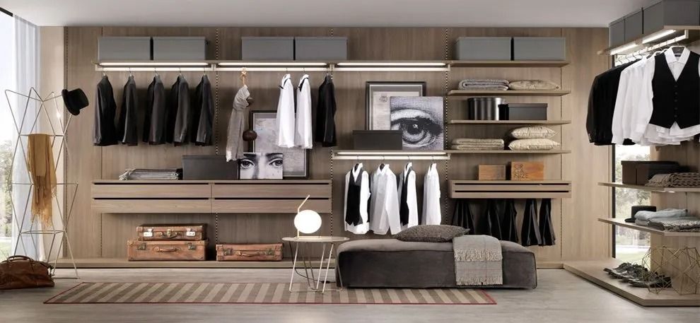 Cabina armadio moderna con ripiani a vista, appendiabiti, cassetti, scarpiera e panca centrale.