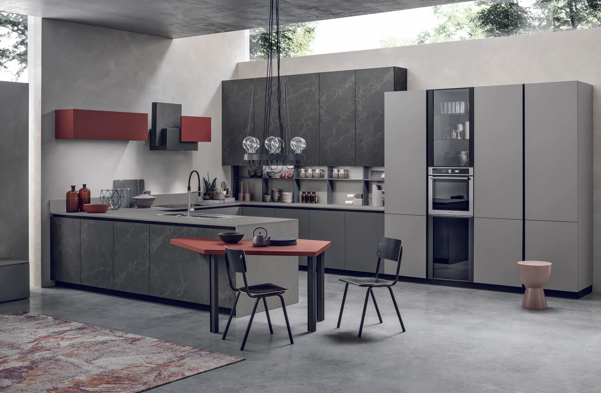 Cucina moderna grigia con isola, dettagli rossi, sgabelli da bar ed elettrodomestici a incasso.