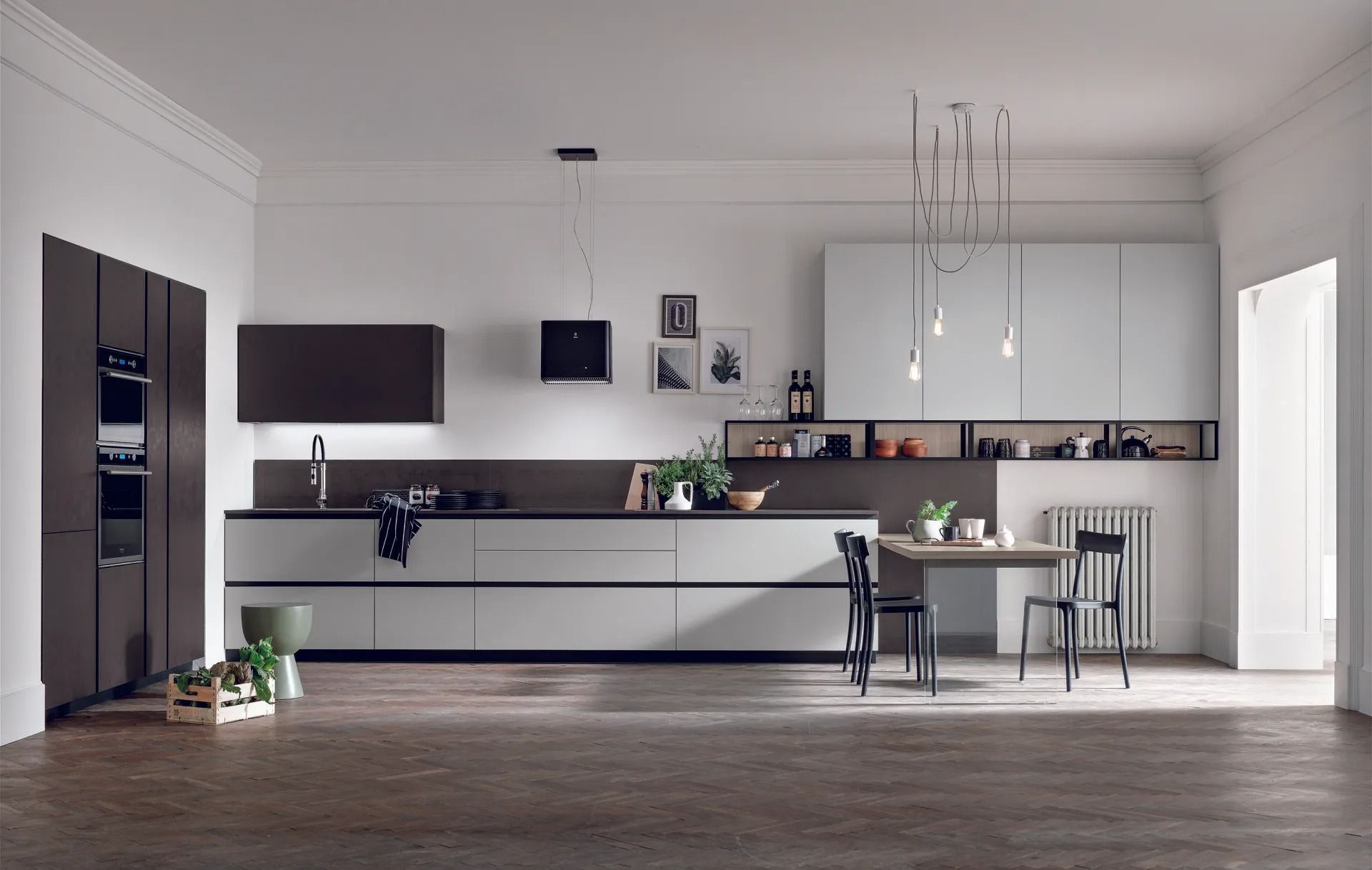 Cucina e zona pranzo moderne a pianta aperta con mobili bianchi, isola scura e grandi lampade a sospensione.