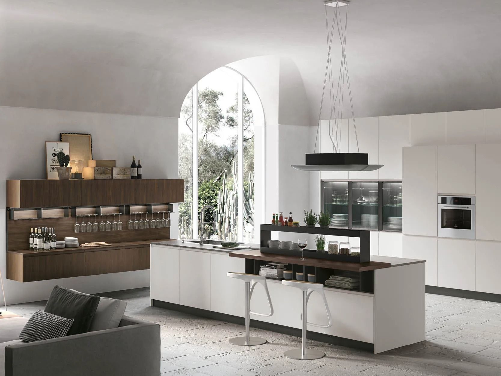 Cucina moderna bianca con isola, ripiani scuri, finestra ad arco ed elettrodomestici a incasso.