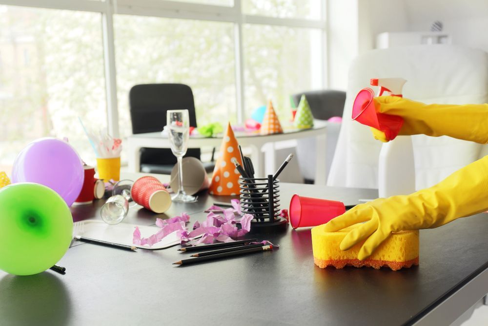 A person wearing yellow gloves is cleaning a table after a party.