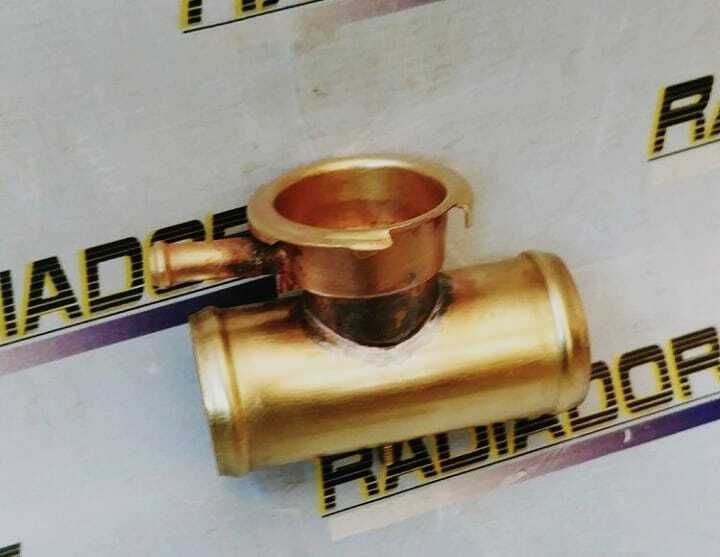 Válvula metálica de color dorado con cuerpo cilíndrico y parte superior abierta, situada sobre una superficie blanca con texto negro.