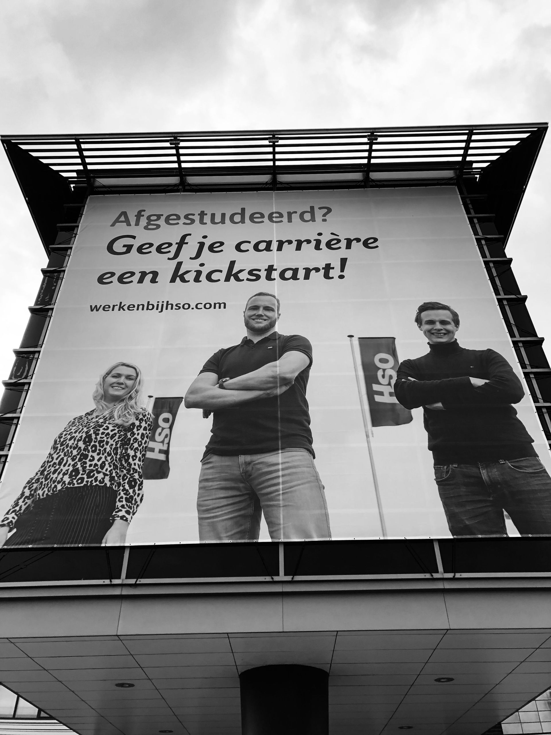 Billboard with three smiling people. Text: 