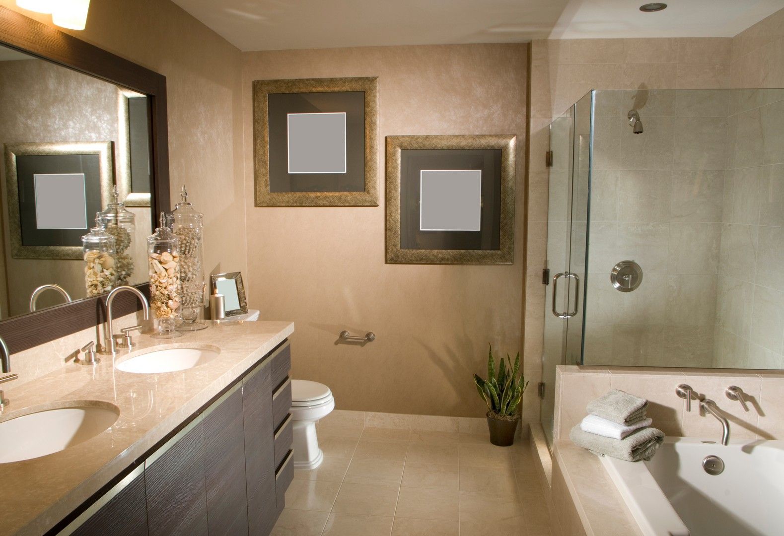 Bagno moderno con mobile lavabo, specchio, vasca da bagno, pareti beige e quadri incorniciati.