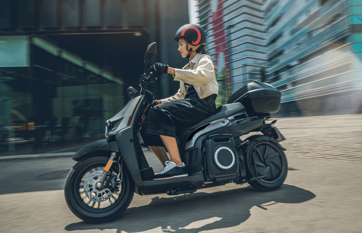 Una donna sta guidando uno scooter elettrico su una strada cittadina.