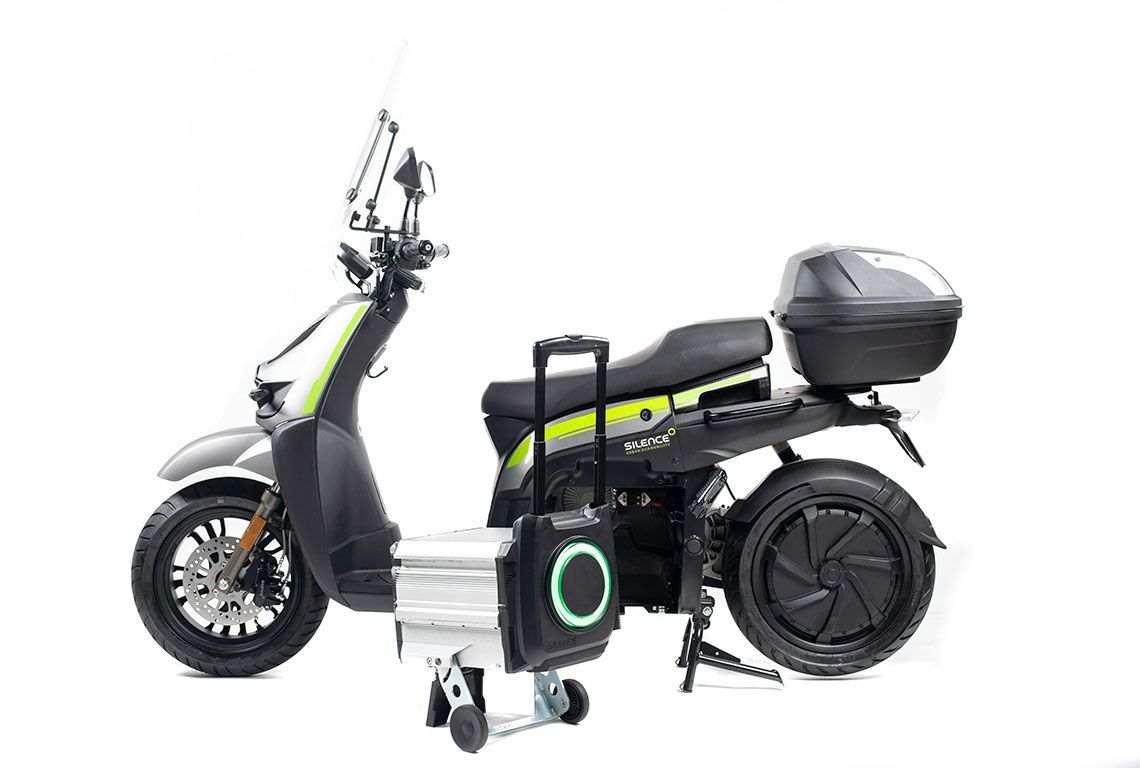 Uno scooter con un altoparlante attaccato è appoggiato su una superficie bianca.