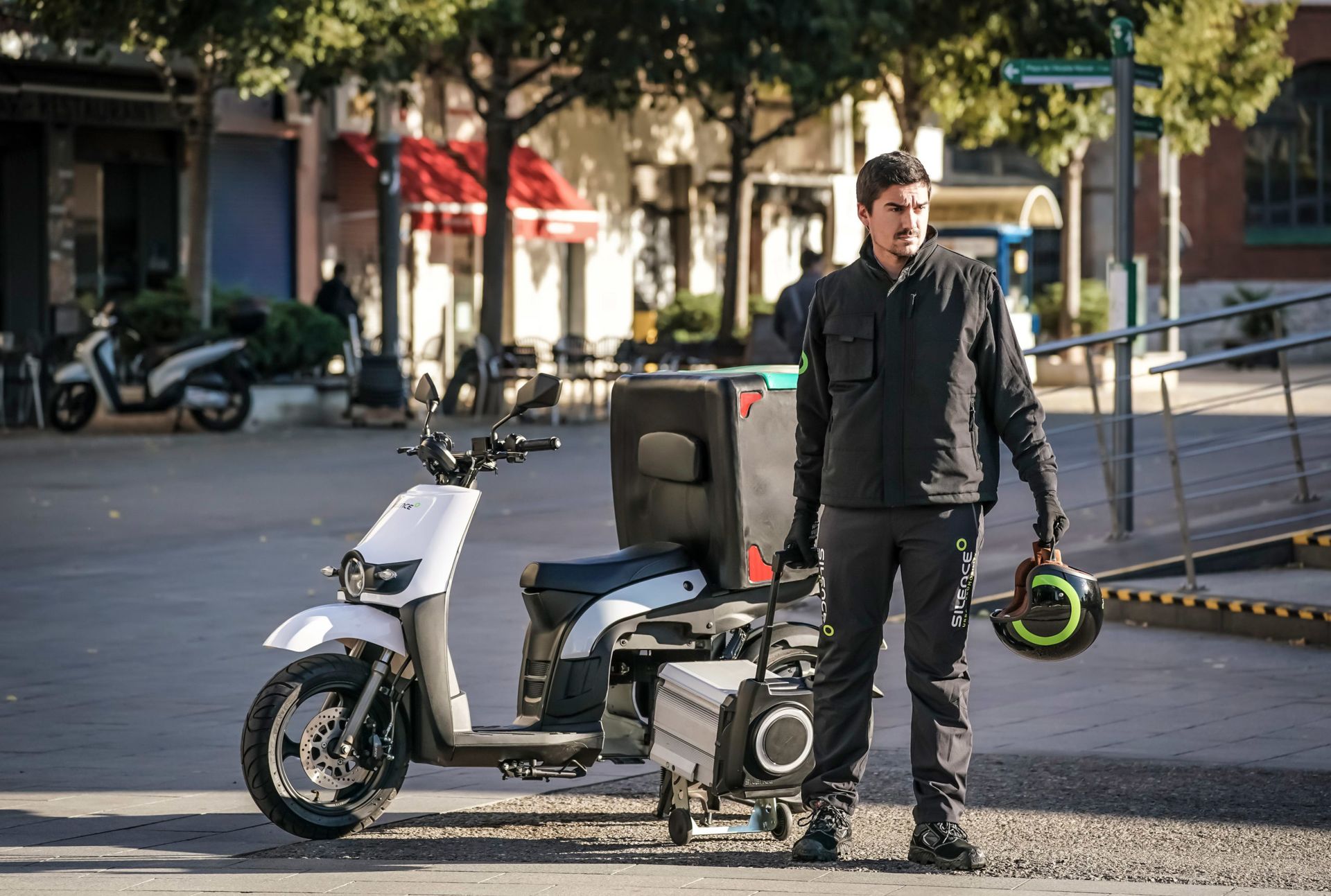 Un uomo è in piedi accanto a uno scooter su una strada cittadina.