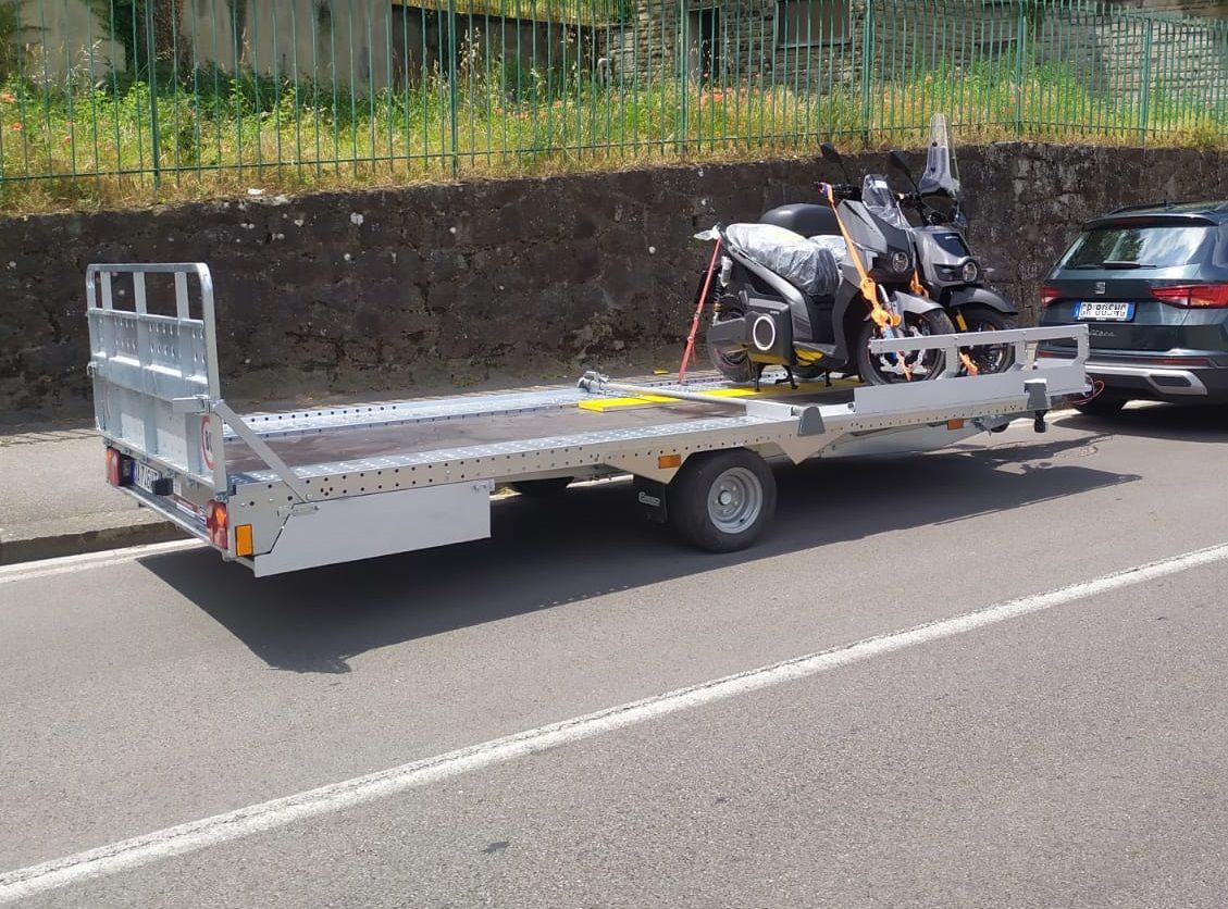Un rimorchio con una motocicletta sopra è parcheggiato sul ciglio della strada.