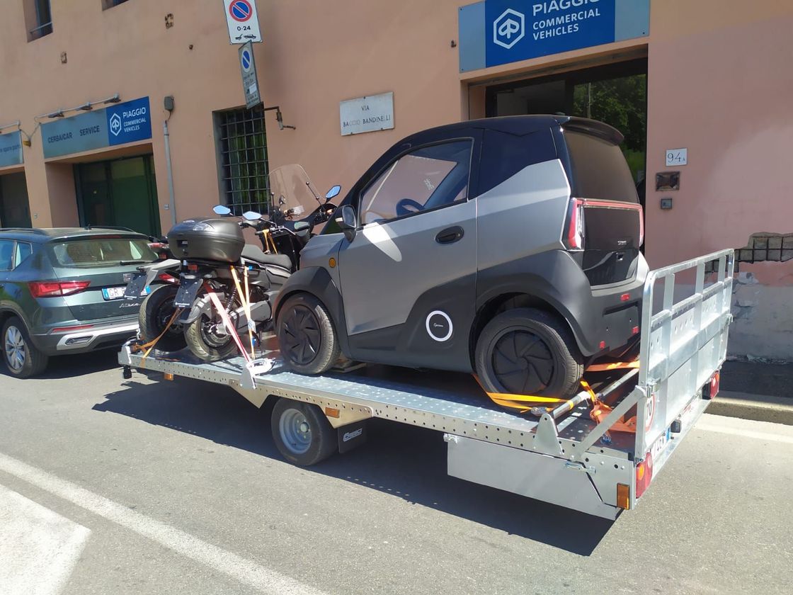 Una piccola automobile viene trainata da un rimorchio.