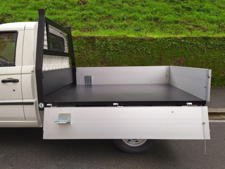 Un camion bianco con un cassone nero è parcheggiato sul ciglio della strada.