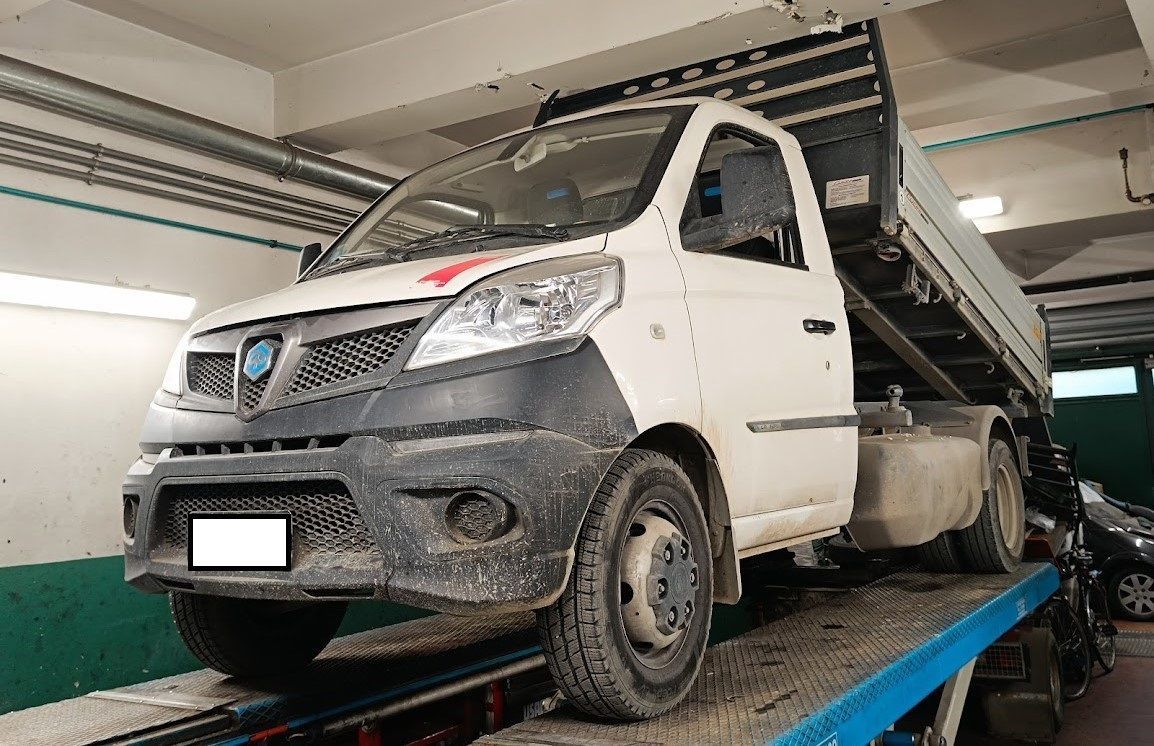 Un camion bianco è parcheggiato sopra un carro attrezzi in un garage.