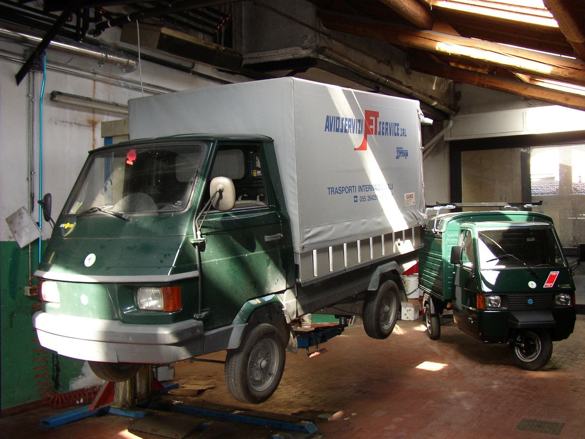 Un furgone verde è parcheggiato in un garage accanto a un furgone bianco
