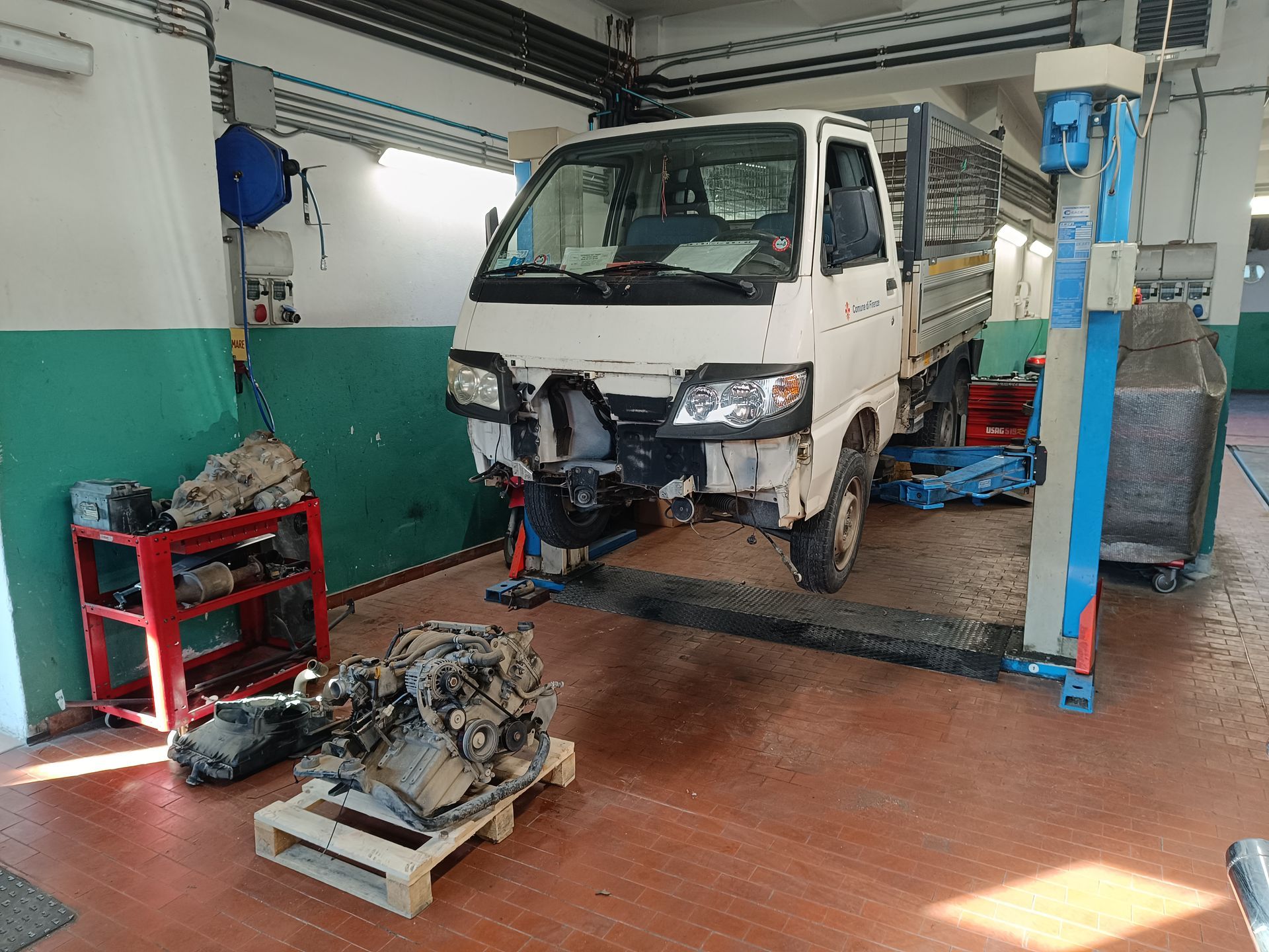 Un camion bianco è parcheggiato su un ponte sollevatore in un garage.