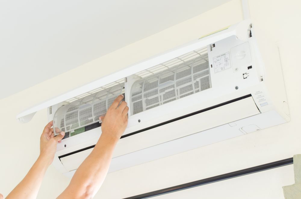 A Person is Cleaning an Air Conditioner With Their Hands  — Revive Air Conditioning in Campbelltown, NSW