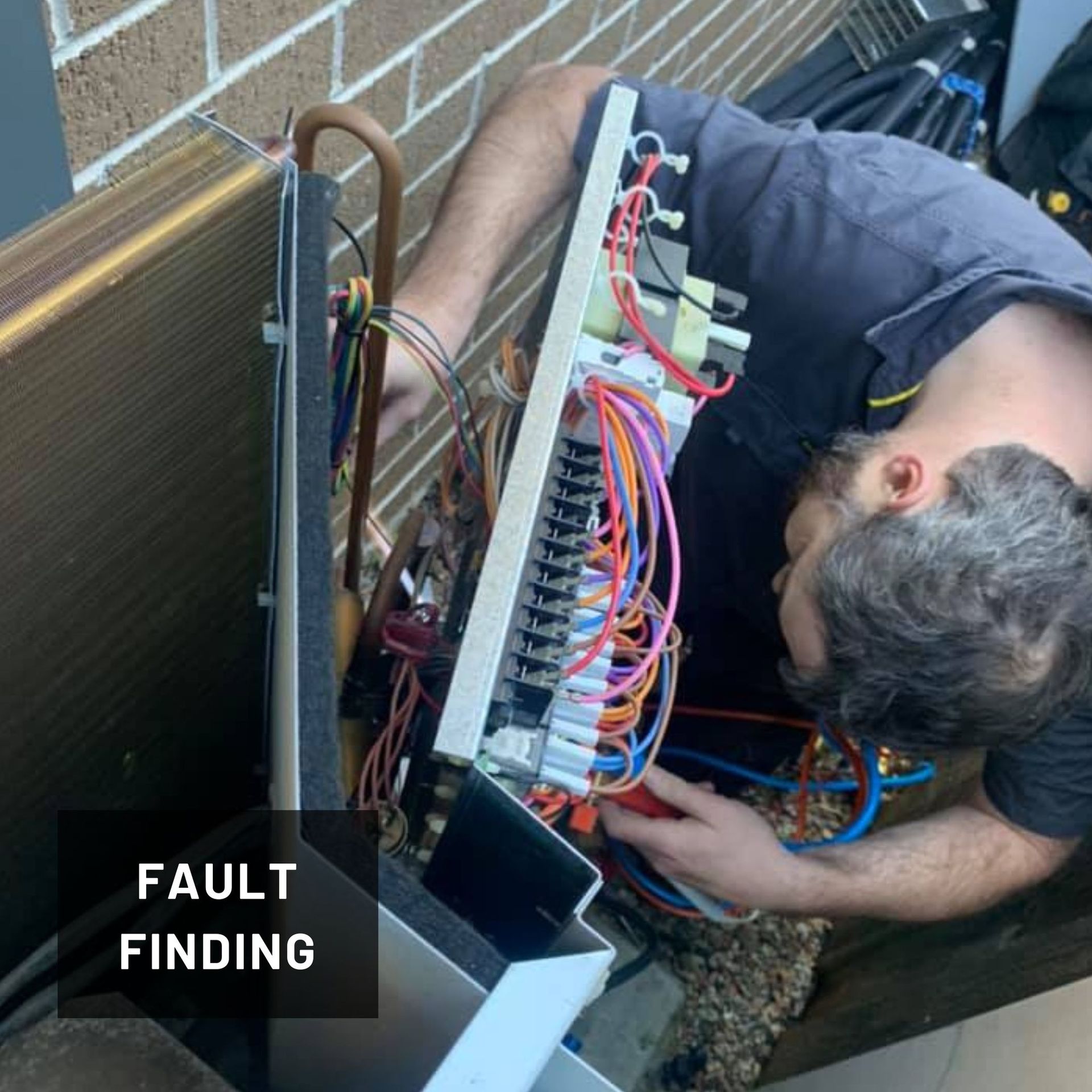 A Man in A Blue Shirt Is Fixing an Air Conditioner — Revive Air Conditioning in Campbelltown, NSW
