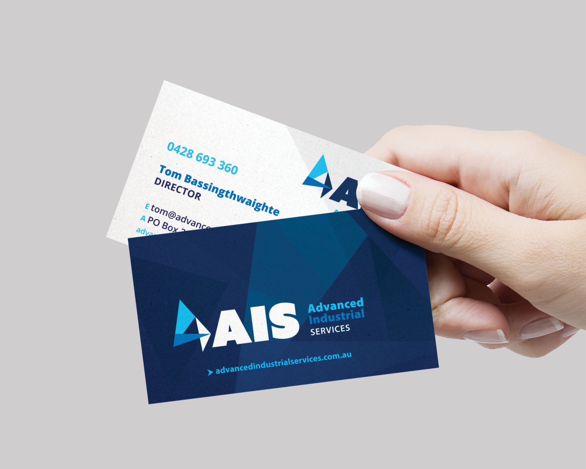 A person is holding two business cards in their hand.