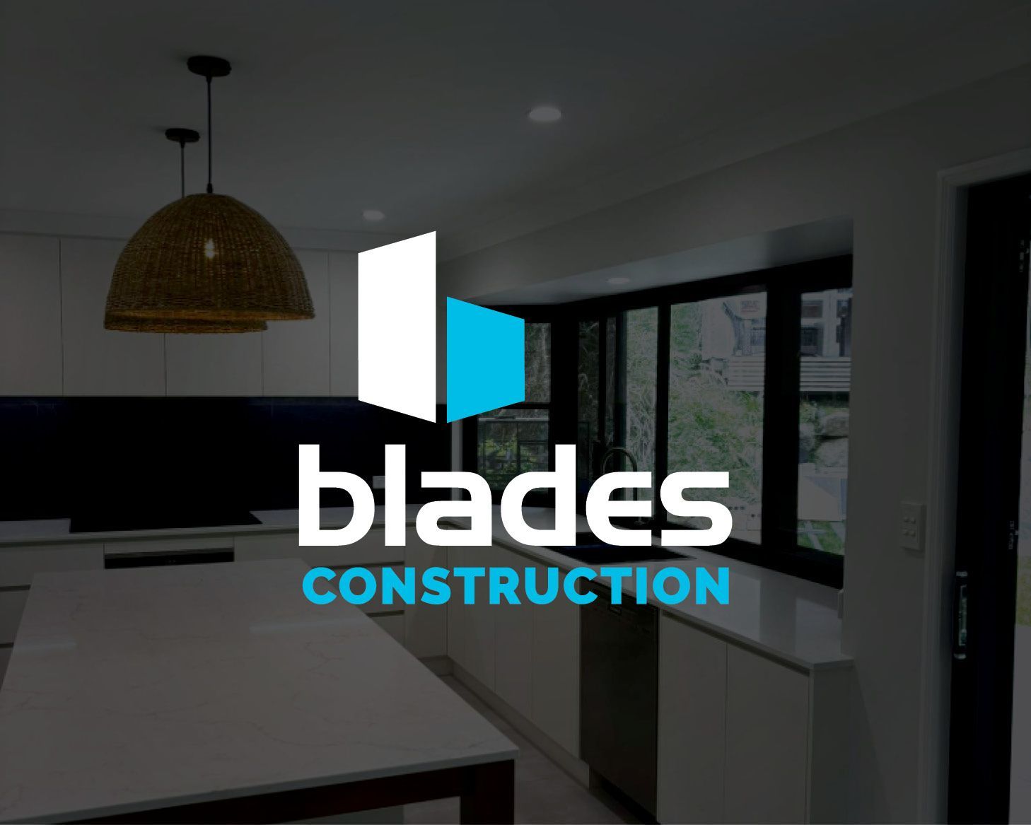 Blades Construction logo over a dim modern kitchen interior with white cabinets and black-framed windows
