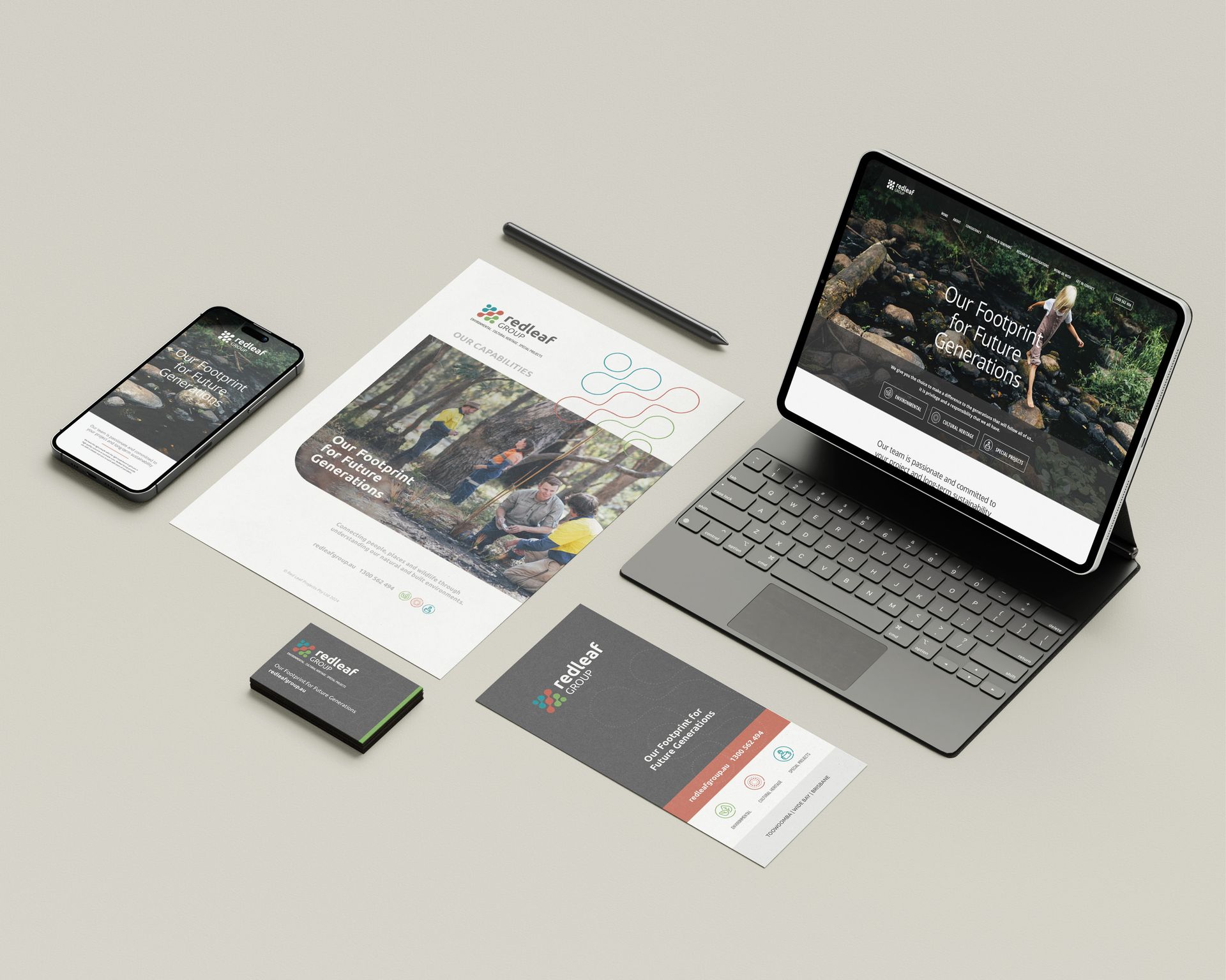 Laptop, phone, and printed business cards with a brochure laid out on a light desk.