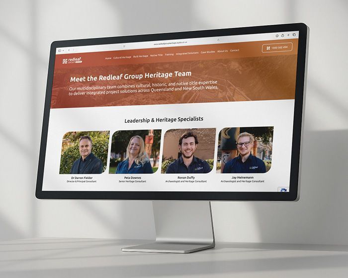 Computer monitor showing a team webpage with four headshots and an orange header.