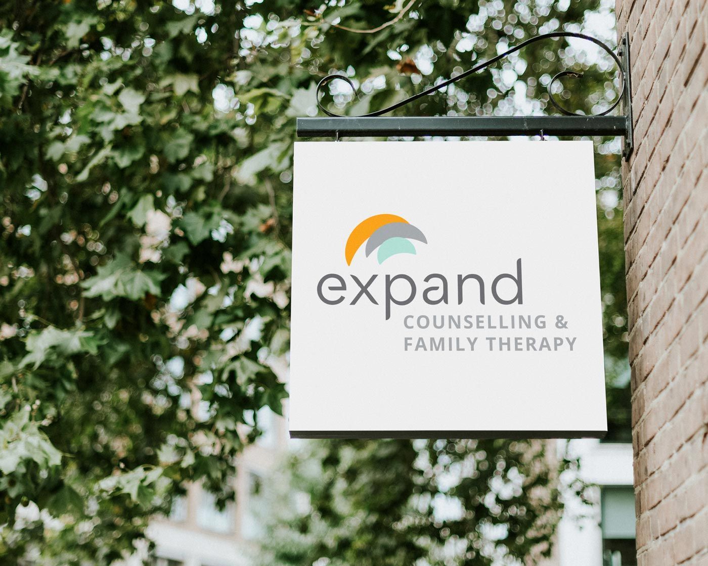 A sign for Expand Counselling and family therapy hangs from a tree