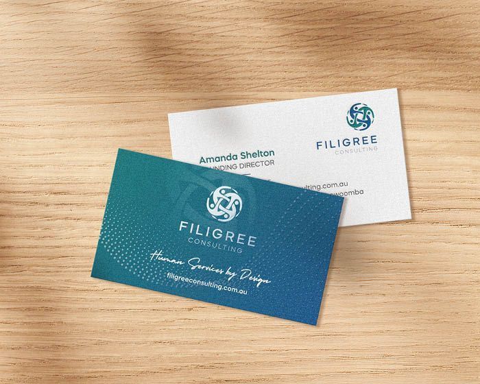 Two business cards are sitting on a wooden table.