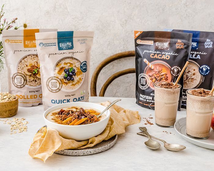 Three oatmeal product pouches, bowls, and two oat milk drinks on a bright tabletop.