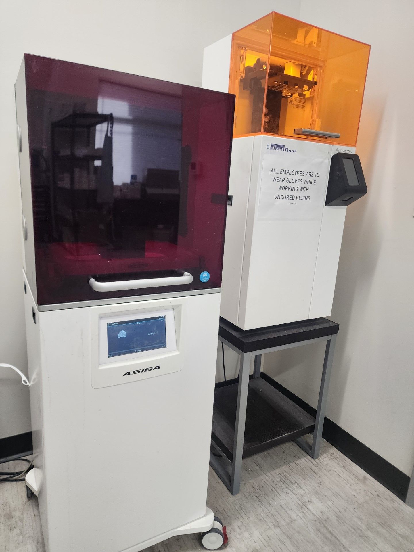 two 3d printers are sitting next to each other in a room