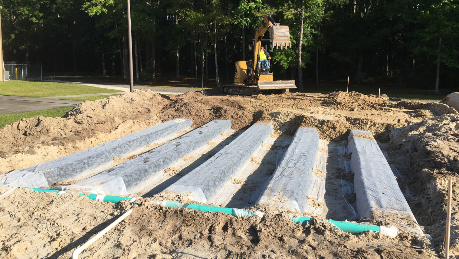 Construction site with stacked concrete slabs in the foreground and an excavator in the background