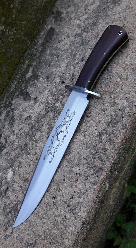 Black-handled fixed-blade knife lying on a rough stone surface.