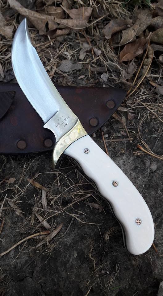 Folded knife with white handle and silver blade resting on dark leather outdoors.
