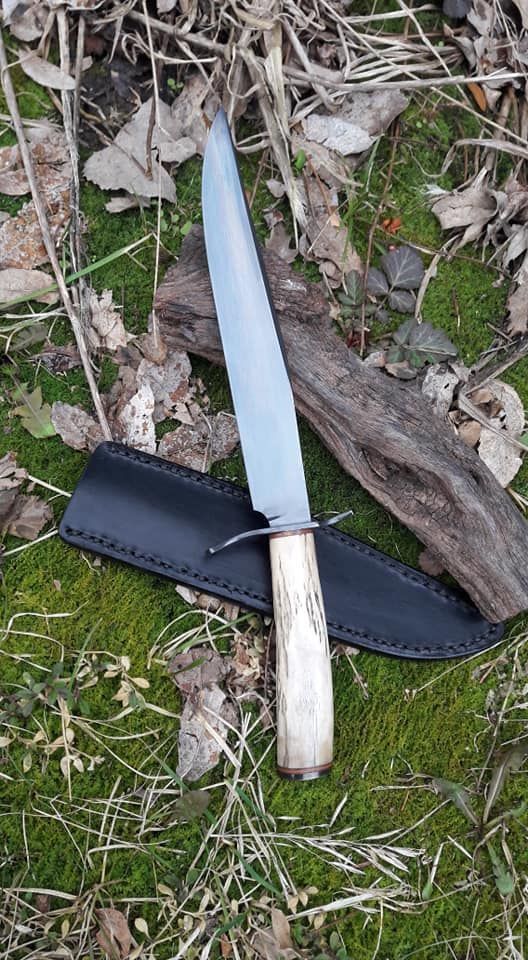 Decorative dagger with a silver handle and patterned blade lying on a stone surface