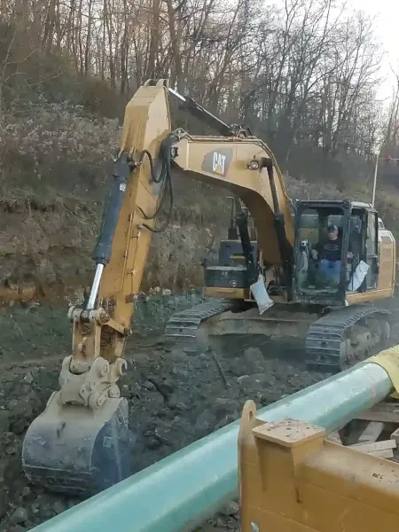 A yellow John Deere 85G excavator sits on a dirt construction site.
