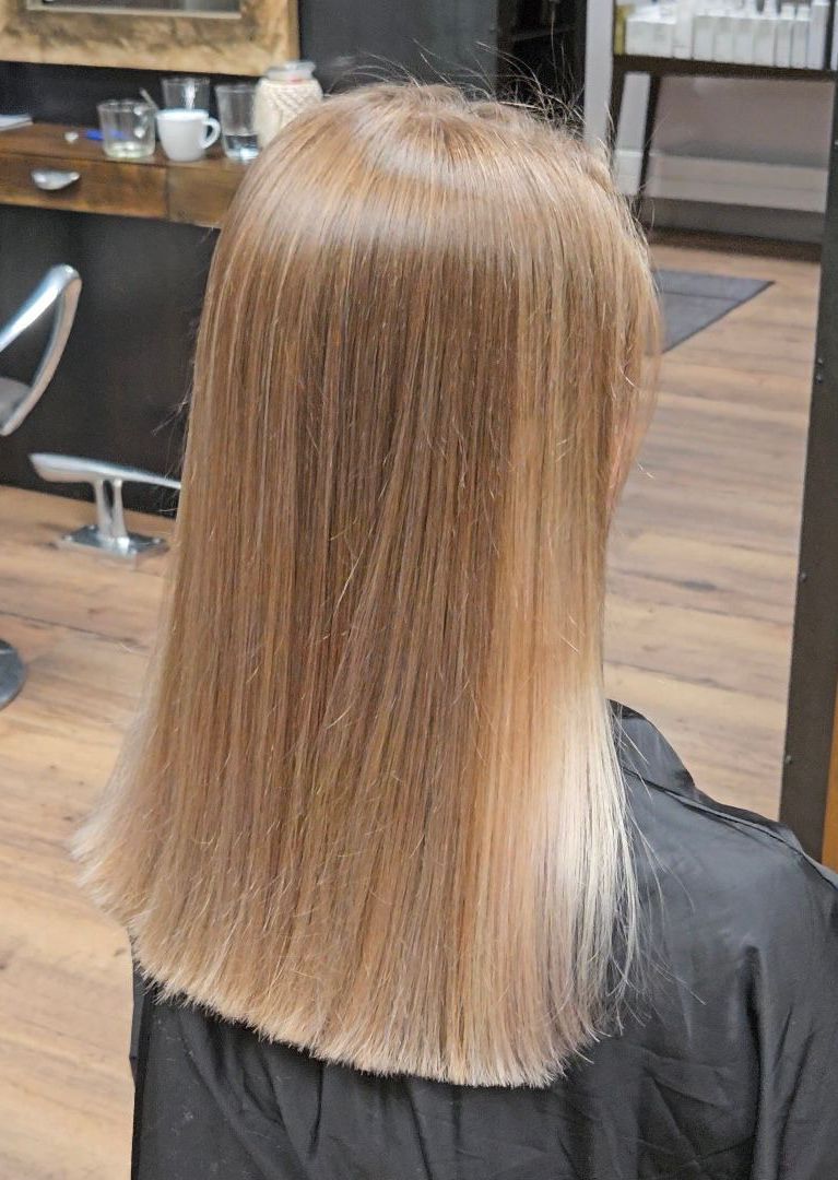 Frau mit langem, glattem, blondem Haar, trägt einen schwarzen Salonumhang.