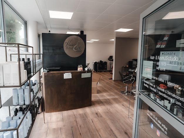 Saloneinrichtung mit Rezeption, Regalen mit Produkten und Blick auf Friseurstühle.