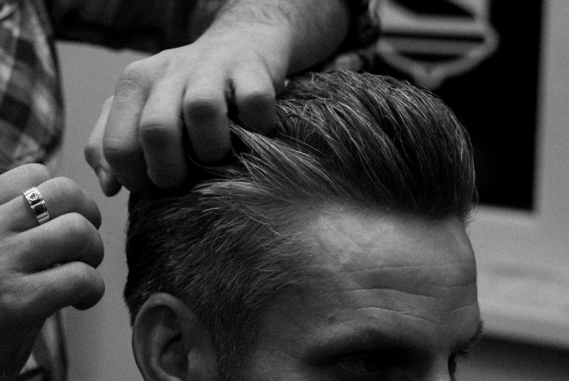 Eine Stylistin kämmt die nach hinten gekämmten Haare einer Kundin in einer Nahaufnahme im Friseursalon.