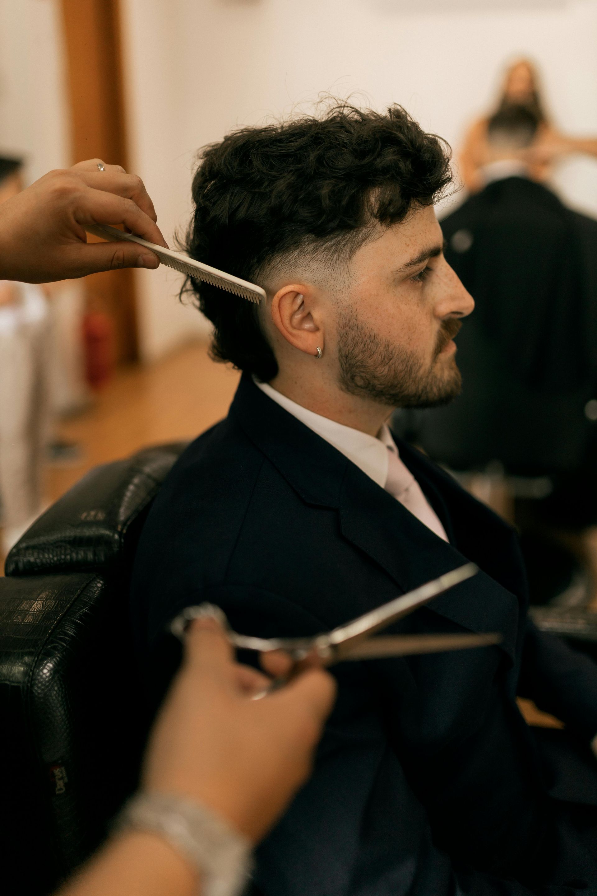 Ein Mann lässt sich im Salon die Haare mit der Schere schneiden.