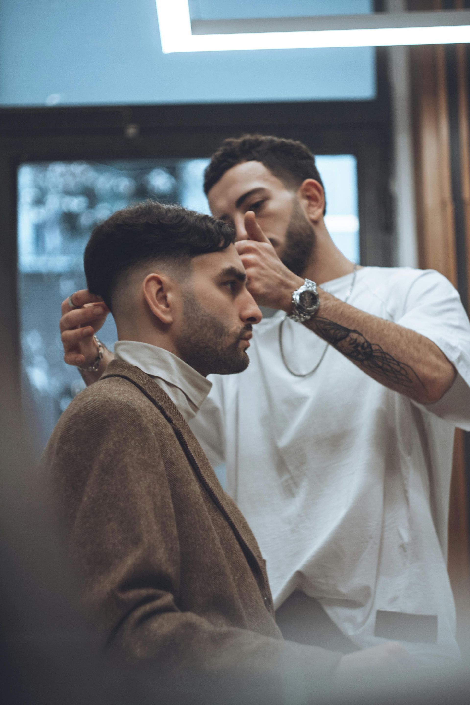 Ein Barbier schneidet einem Mann in einem modernen Salon die Haare; der Kunde sitzt in einem braunen Umhang.