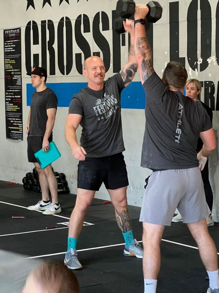 A man is lifting a dumbbell over his head in a gym.