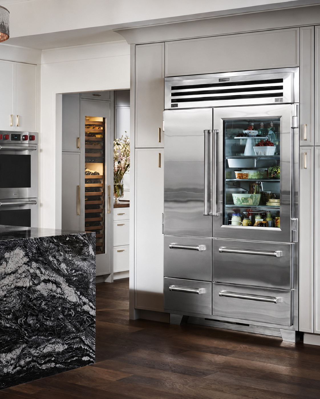 Modern kitchen with stainless steel refrigerator and open pantry, dark wood floor, and black marble island