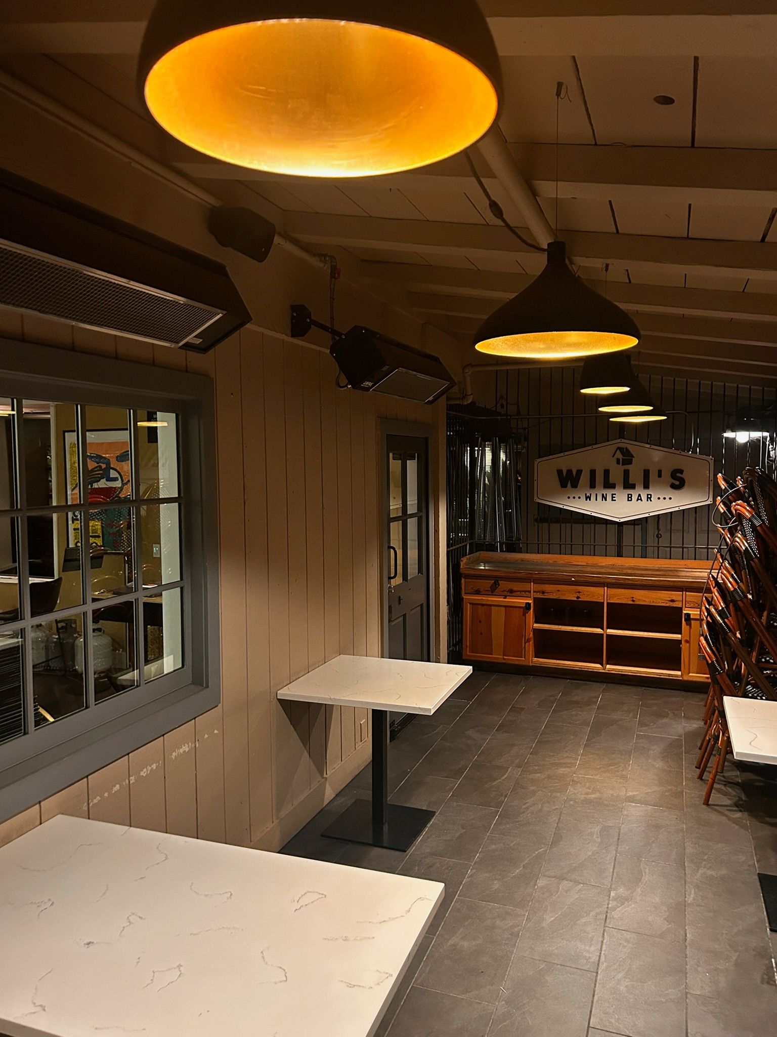 Outdoor bar area with tables, overhead lights, and a sign that reads 