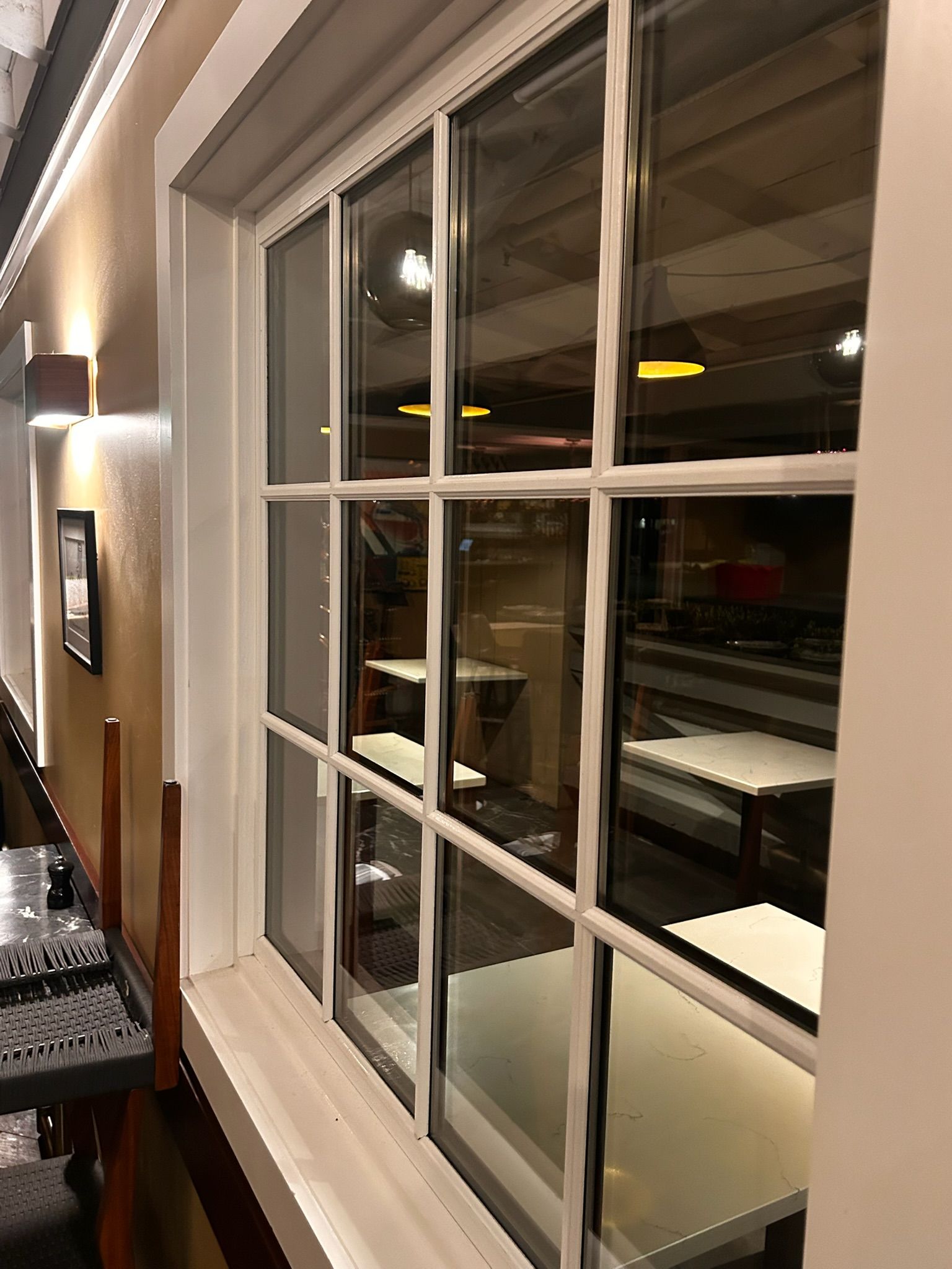White-framed window with multiple panes reflecting an interior with tables and a bar area.