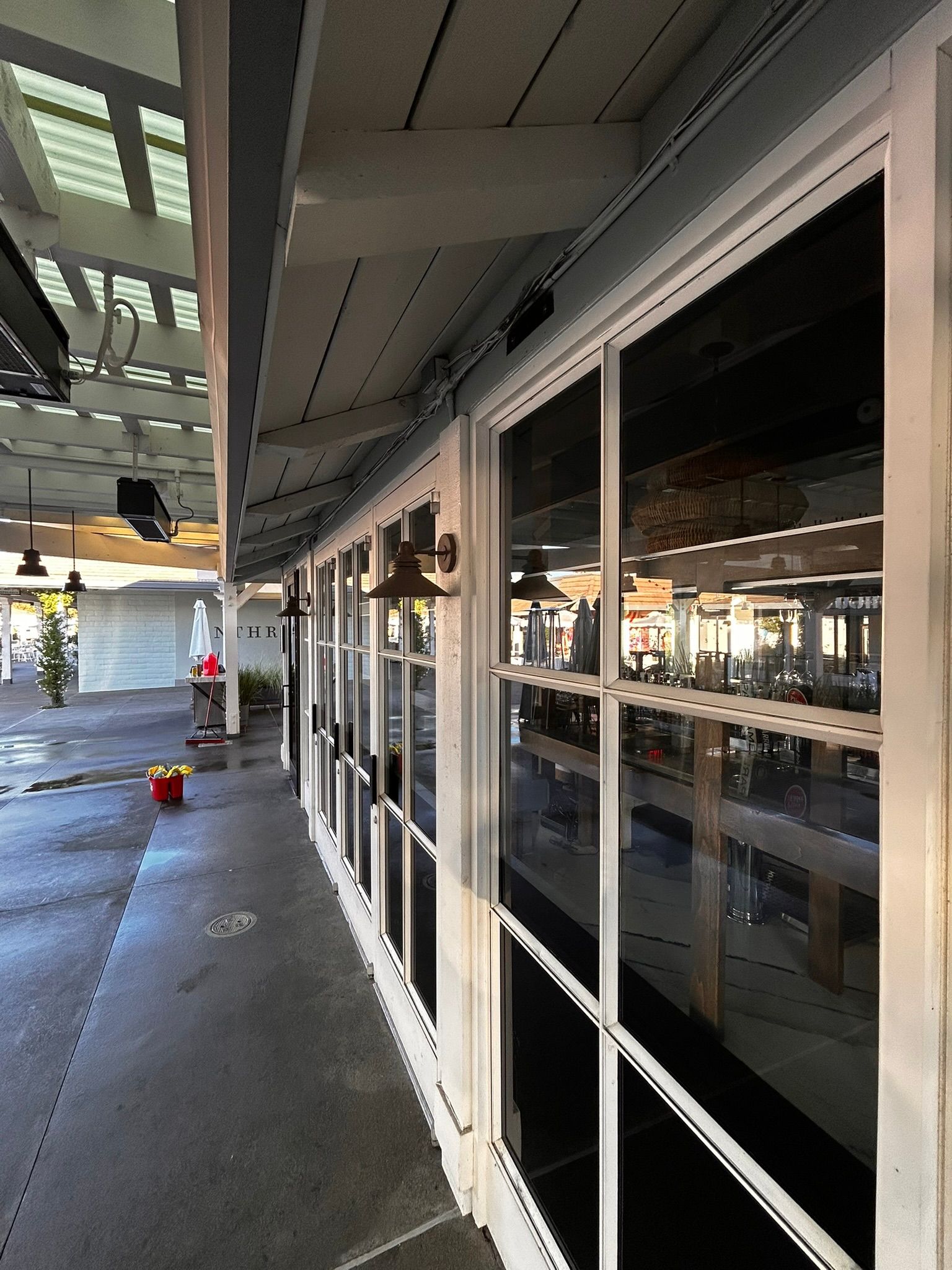 Exterior of a building with white-framed windows reflecting interior. A walkway with a red fire hydrant is on the left.